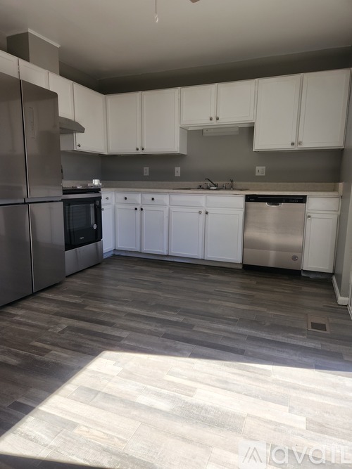 A kitchen with white cabinets and a grey floor.