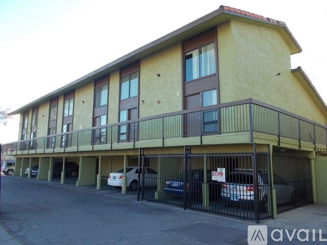 A building with a balcony and cars parked in front.