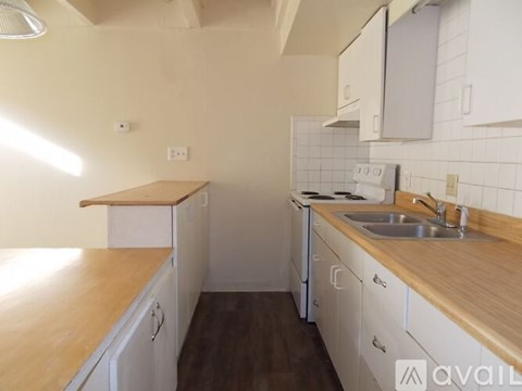 A kitchen with white cabinets and a wooden countertop.