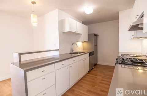 A kitchen with white cabinets and a wooden floor.