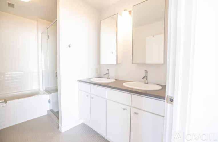 A white bathroom with a tub, sink, and mirror.