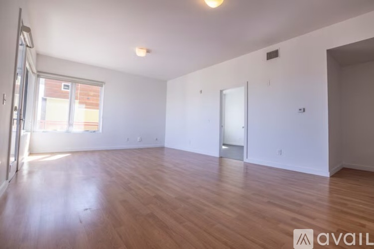 A spacious room with wooden flooring and white walls.