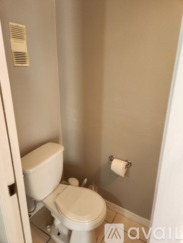 A white toilet in a bathroom with a toilet paper roll on the wall.