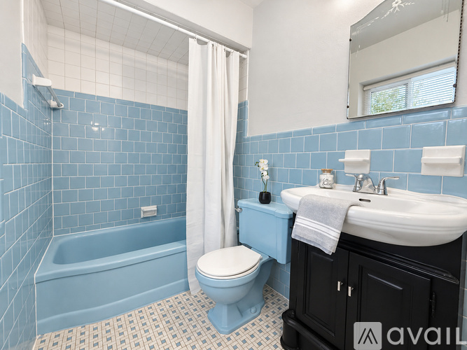 A bathroom with blue tiles and a white sink.