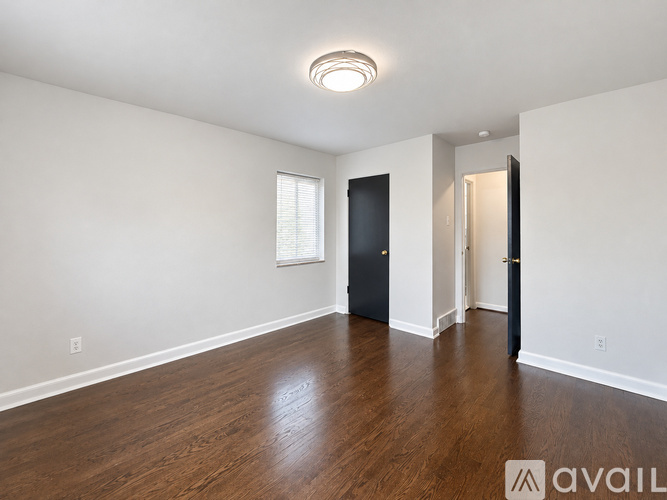 A spacious room with wooden floors and a black door.