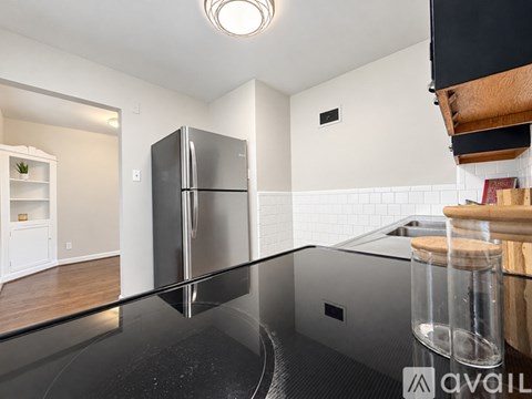 A kitchen with a black fridge and a window with blinds.