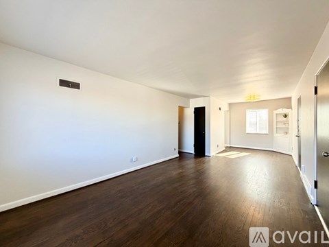 A spacious room with wooden floors and white walls.