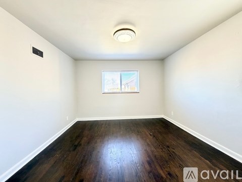 A room with wooden floors and a window showing a building outside.