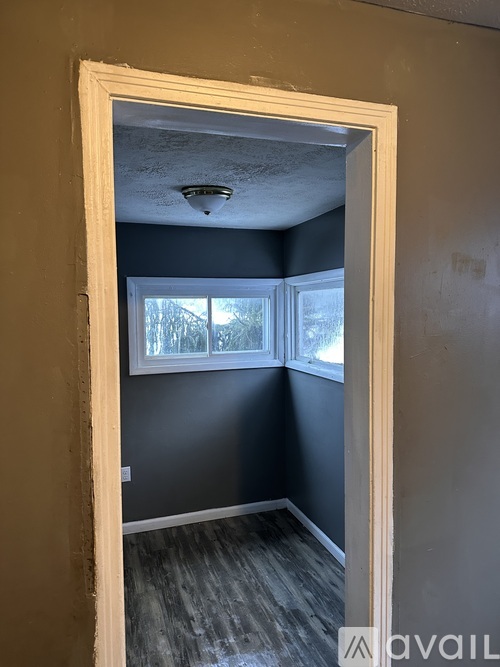 A room with a window and a doorway leading to another room.