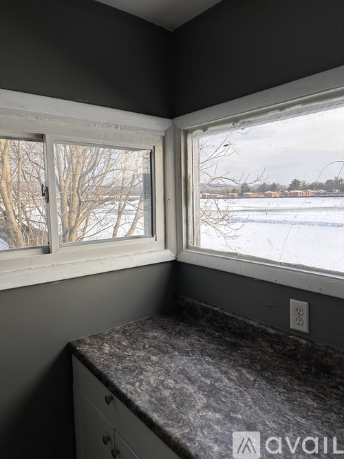 A kitchen counter with a window overlooking a snowy landscape.