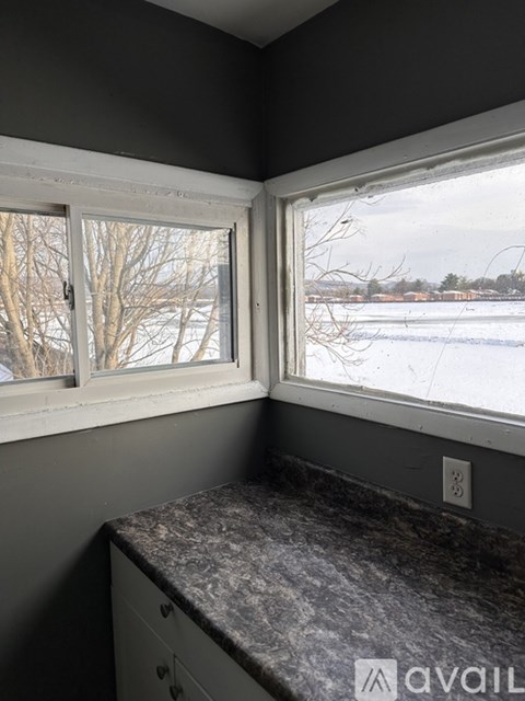 A kitchen counter with a window overlooking a snowy landscape.