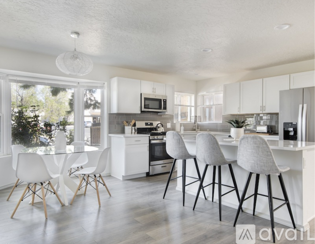 A modern kitchen with white chairs and a wooden table.