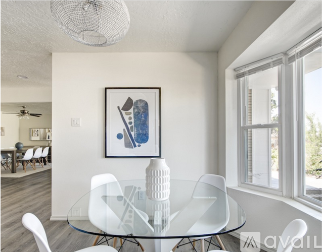 A modern dining room with a glass table and white chairs.