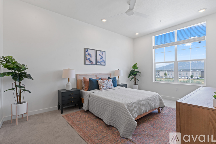 A bedroom with a large bed, a nightstand, and a window overlooking the city.