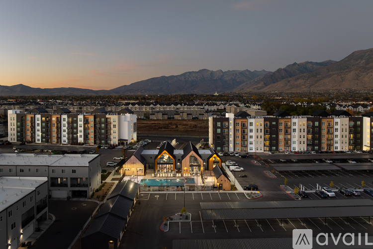 A large building complex with a parking lot in front and mountains in the background.