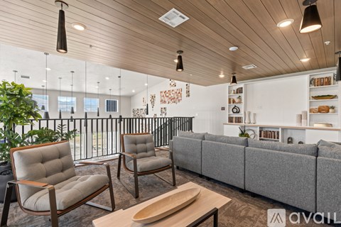 A living room with a grey couch, two chairs and a coffee table.
