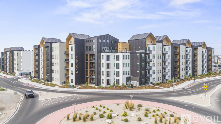 A row of modern apartment buildings are lined up along a street.