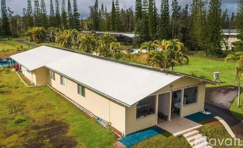 A house with a white roof and a blue pool in the yard.