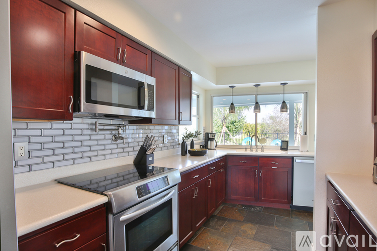 A kitchen with dark wood cabinets and stainless steel appliances.
