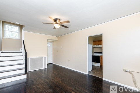 A room with a ceiling fan and a staircase.