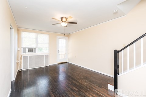 A room with a ceiling fan and wooden floors.