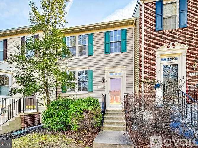A house with a grey facade and a pink door is for sale.