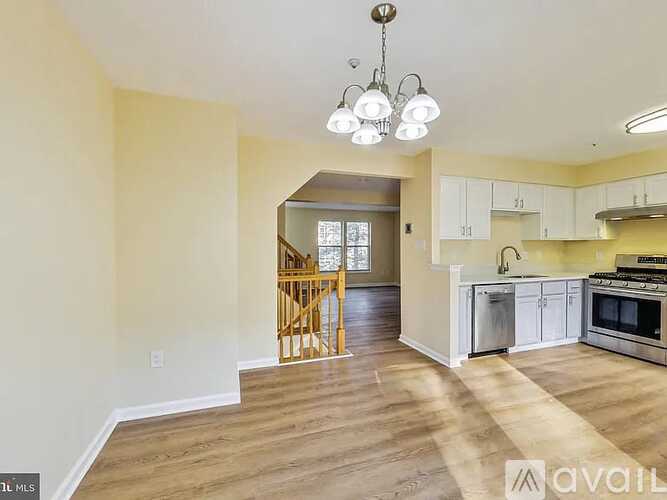 A kitchen with white cabinets and a wooden floor.