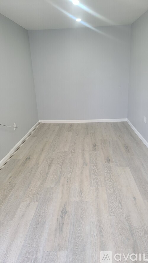 A room with wooden flooring and white walls.