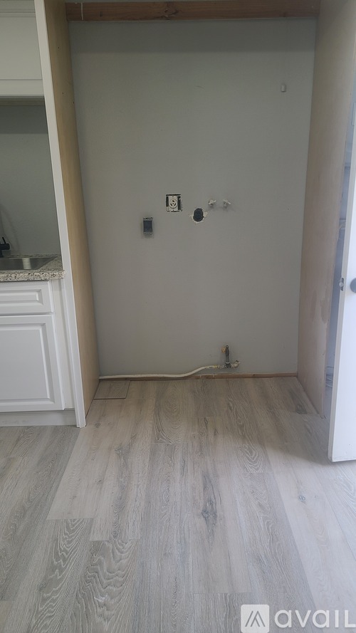 A room with a white wall and wooden floor.