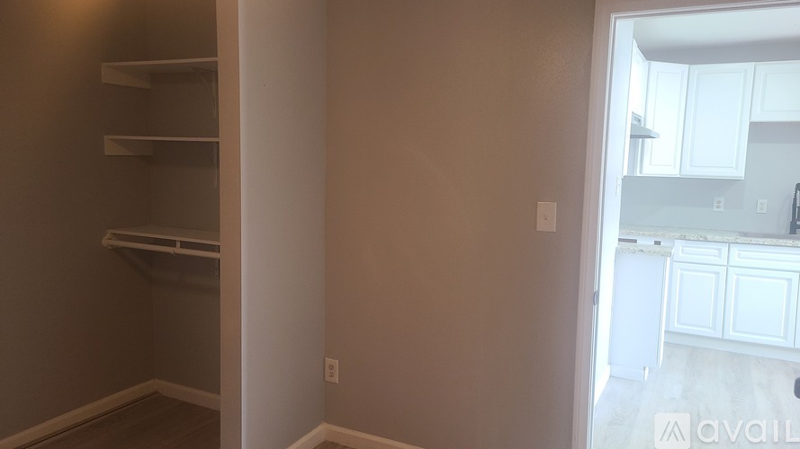 A room with a white door leading to a kitchen.