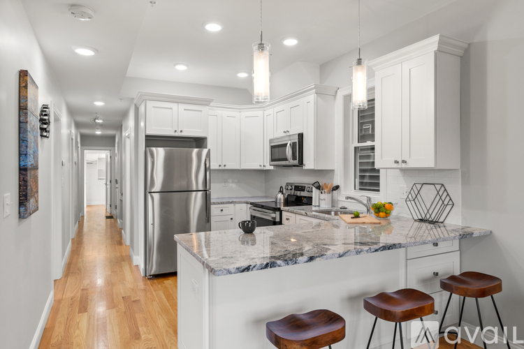 A kitchen with white cabinets and a marble countertop.