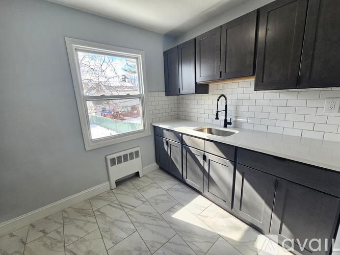 A kitchen with a window, sink, and black cabinets.