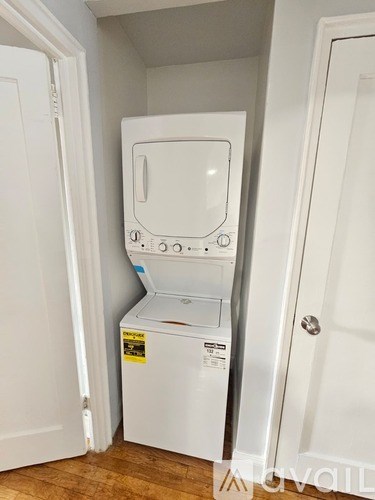 A white dishwasher is in a small space between two white doors.