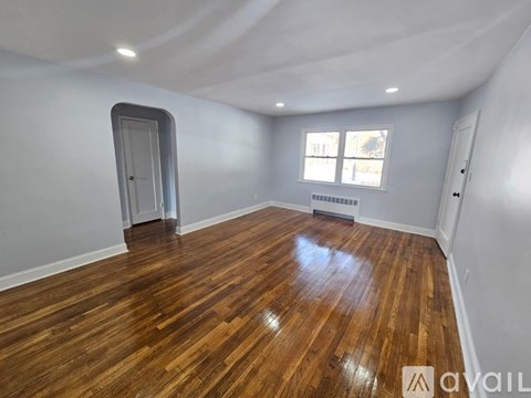 A room with wooden flooring and a window with blinds.