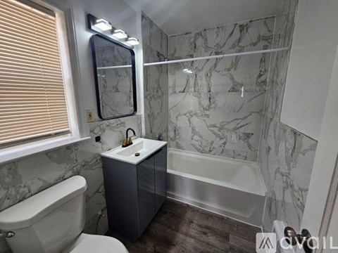 A bathroom with a marble wall and a white bathtub.