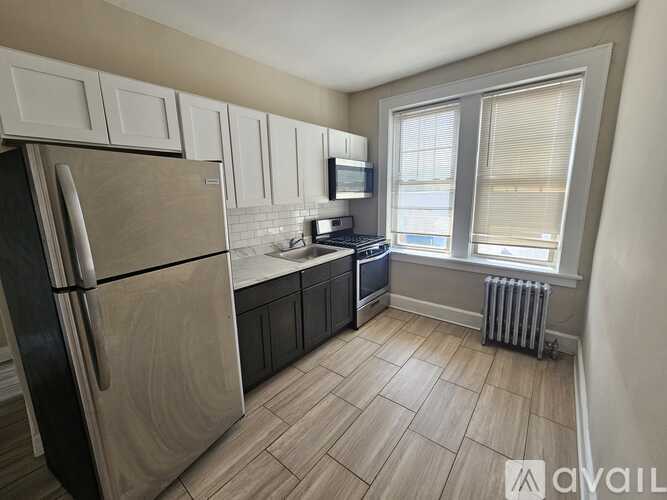 A kitchen with a refrigerator, microwave, and a window.