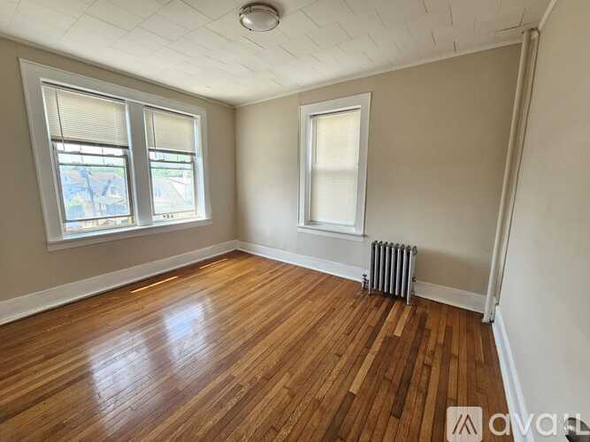 A room with wooden floors and two windows.