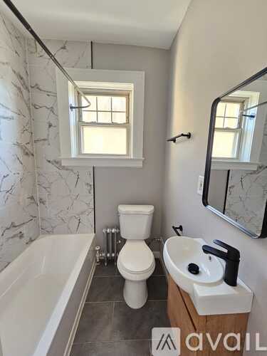 A bathroom with a tub, toilet, and sink.