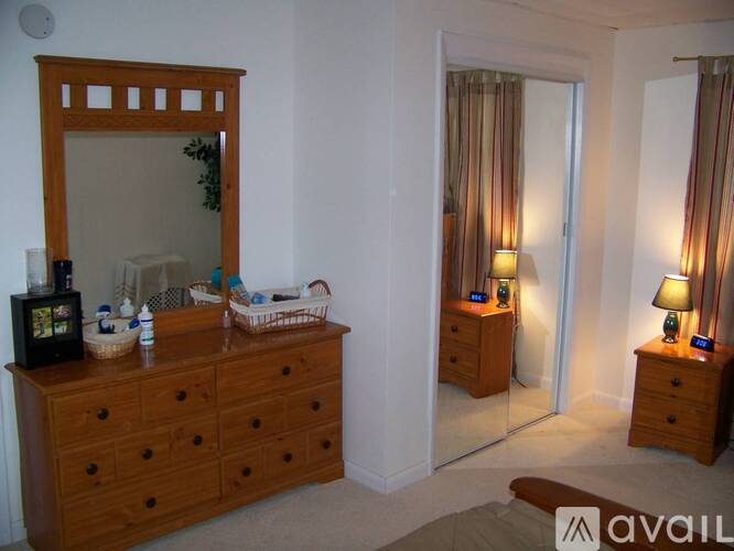 A bedroom with a wooden dresser and a mirror.