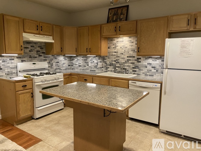 A kitchen with a white fridge, white stove, and wooden cabinets.