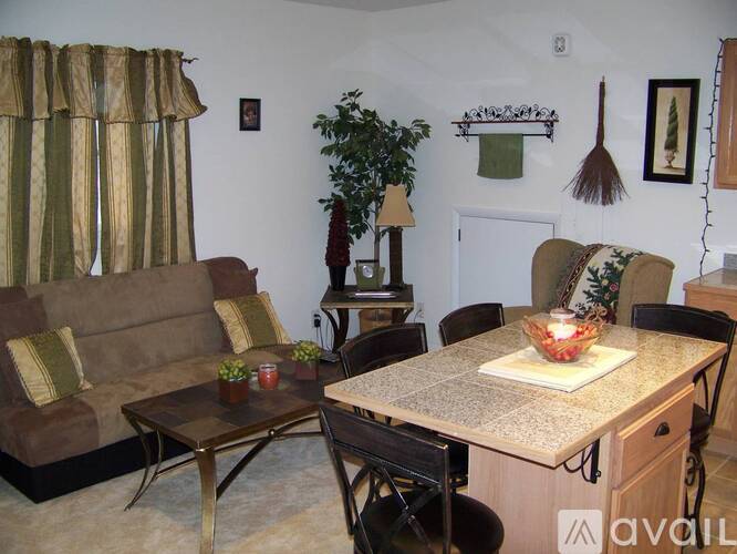 A living room with a couch, chairs, and a table with a bowl of fruit on it.
