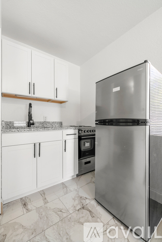 A kitchen with a stainless steel refrigerator and white cabinets.
