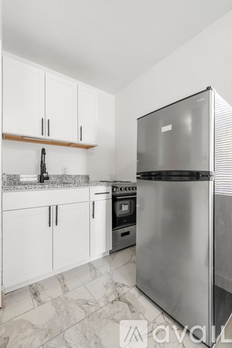 A kitchen with a stainless steel refrigerator and white cabinets.