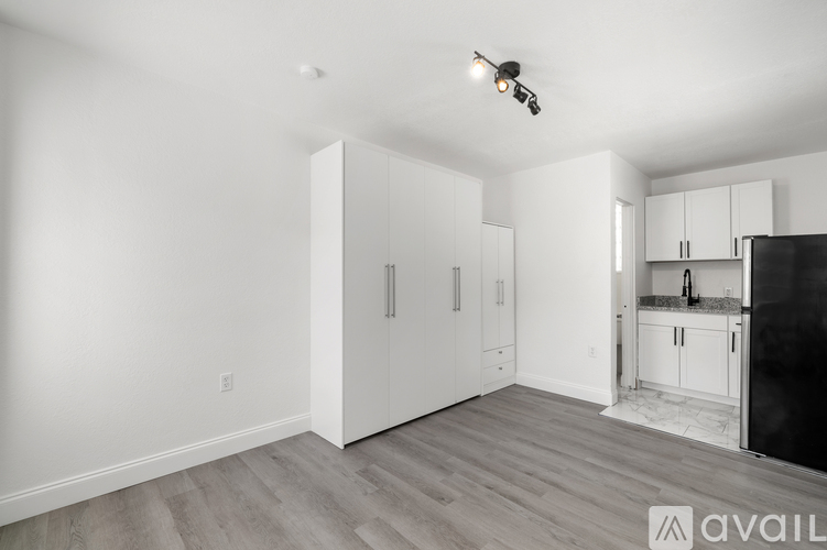 A kitchen area with white cabinets and a black refrigerator.