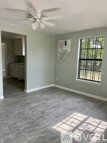 A room with a ceiling fan and a window with bars.