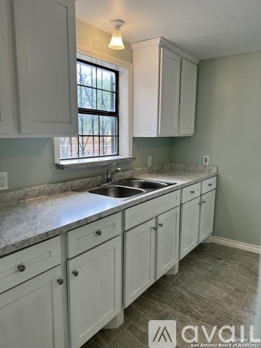A kitchen with white cabinets and a marble countertop.