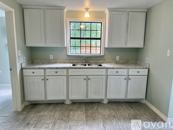 A kitchen with white cabinets and a marble countertop.
