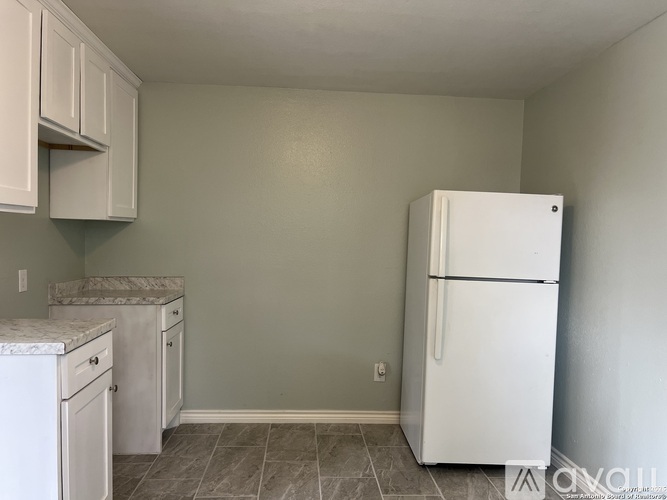 A kitchen with a white fridge and cabinets.