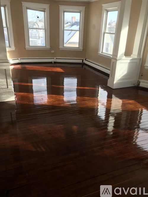 A room with wooden floors and three windows.