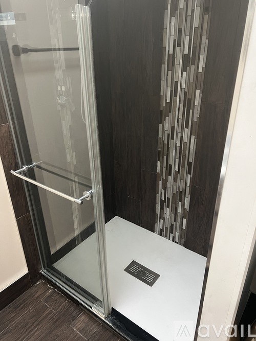 A glass shower door with a white frame and a black handle.